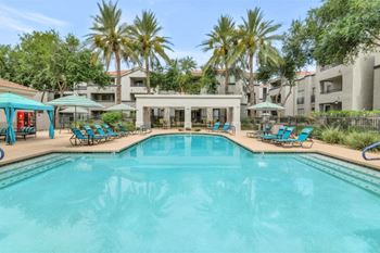 Resort style swimming pool with cabanas and palm trees
